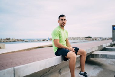 30 'lu yaşlardaki kararlı sporcunun dinlenme saatinde kameraya baktığı beyaz erkek atletizm sporcusu antrenman sırasında fiziksel canlandırma için poz veriyor.