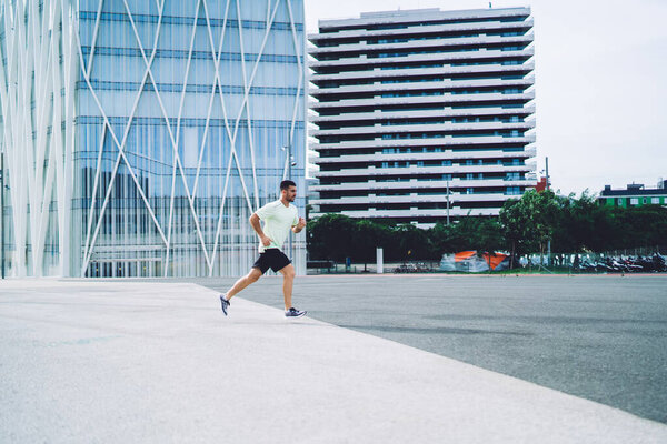 Side view of male athlete jogging with endurance enjoying morning training at city street for running, strong man in sportswear have cardio workout training during leisure for intensive practice