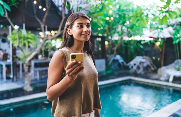 Tatil sırasında gülümseyerek yüzünü çevirmiş verandada havuz ve kafe karşısında gündelik giyinmiş genç etnik bayan otel misafiri olmaktan memnuniyet duyuyorum.