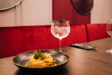 Tahta masada servis edilen taze böğürtlenlerle süslenmiş bir bardak soğuk alkol kokteyli.