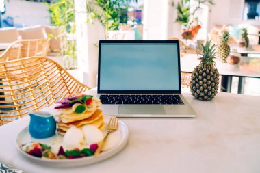 Ananas ve tabağın yanına beyaz ekran dizüstü bilgisayarla sağlıklı kahvaltı, krep ve Bali 'de meyve.