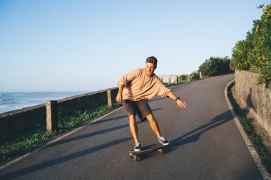 Profesyonel hippi kaykaycı asfalt yolda gündelik kıyafet eğitimi alıyor. Deniz kenarında boş zamanlarının tadını çıkarıyor. Kırsal alanda tatil yapmaktan memnun olan 20 'li yaşlardaki yetenekli beyaz erkek.