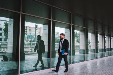 Zarif takım elbiseli, şık saç kesimli, gülerken camdan duvarda yürüyen saygıdeğer, mutlu iş adamlarının tüm vücudu.