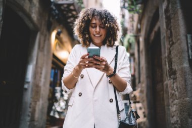 Kafkasyalı hippi kız internet sitesine girip akıllı telefon cihazında web metni okuduğu için 4G 'ye bağlanıyor. Cep telefonu teknolojisiyle çevrimiçi mesajlaşma sırasında gelen e-postaları kontrol eden büyüleyici bayan turist.