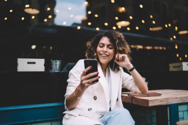 Neşeli hippi kız kulaklıklarıyla komik videolar izliyor ve gülümsüyor. Boş zamanlarını kaldırımdaki kafede geçiriyor. Komik kadın milenyumu akıllı telefon konuşmaları ve pozitif müzik listesiyle eğleniyor.