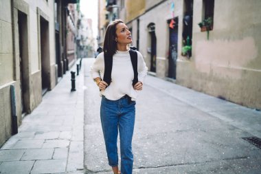 Seyahat sırt çantalı beyaz kadın turist, tarihi bölgede tek başına geziyor, 30 yaşında sıradan giyinmiş bir kadın, uluslararası şehir gezisi sırasında şehir sokaklarını keşfediyor.