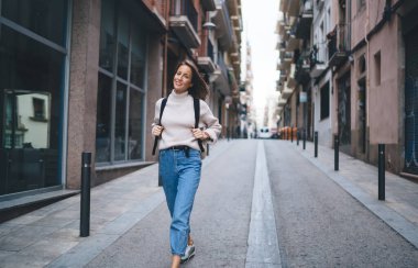 Sırt çantalı mutlu beyaz kadın portresi turistik şehirde geziyor ve sokak mimarisini keşfediyor, tasasız 30 'lu yaşlardaki kadın gezgin uluslararası tatillerde şehri ziyaret ediyor.