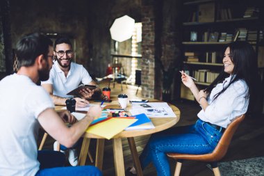 Cheerful group of multiracial colleagues enjoying cooperate teamwork for discussing organization plan, smiling hipster creators have distance brainstorming for collaboration in coworking space
