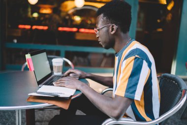 Young male user installing application for creating blog publication reading web instruction on laptop technology, skilled hipster guy searching content information while browsing wireless on netbook
