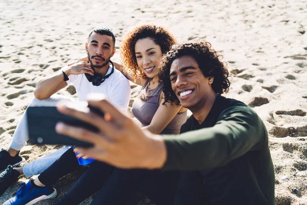 一组快乐的 喜欢团队合作的人坐在沙滩上 在智能手机前置摄像头前微笑 创造了照片内容 快乐的训练员拍摄了视频日志 — 图库照片