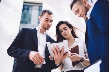 Proje üzerinde çalışırken sokakta ve tablette birlikte duran çok ırklı resmi meslektaşların düşük açısı