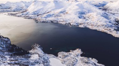 Kışın karla kaplı fiyort dağlarının nefes kesici kuş bakışı görüntüsü. Hava manzaralı kaya zirveleri, resimli güzel doğa manzarası. Lofoten Adası İskandinav bölgesiyle çevrilidir