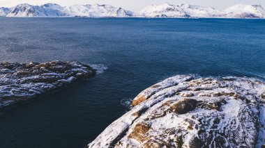 Kışın karla kaplı görkemli fiyort dağlarının nefes kesici kuş bakışı görüntüsü. Hava manzaralı kaya zirveleri, resim gibi güzel doğa manzarası. Norveç, Lofoten Adası. 