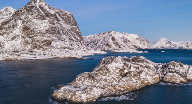 Kışın karla kaplı görkemli fiyort dağlarının nefes kesici kuş bakışı görüntüsü. Hava manzaralı kaya zirveleri, resim gibi güzel doğa manzarası. Lofoten Adası İskandinav Denizi ile çevrilidir