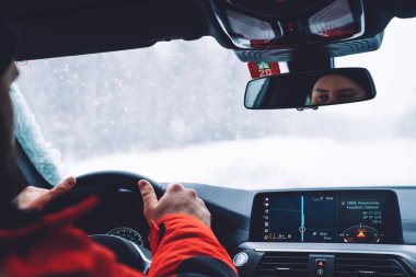 Wildwood varış yerindeki beyaz karlı yolda güvenli bir şekilde giden bir adamın ellerinin görüntüsü. Bir erkek aynaya bakıyor. Arabayla keşif yapıyor. Seyahatte sigortası var.