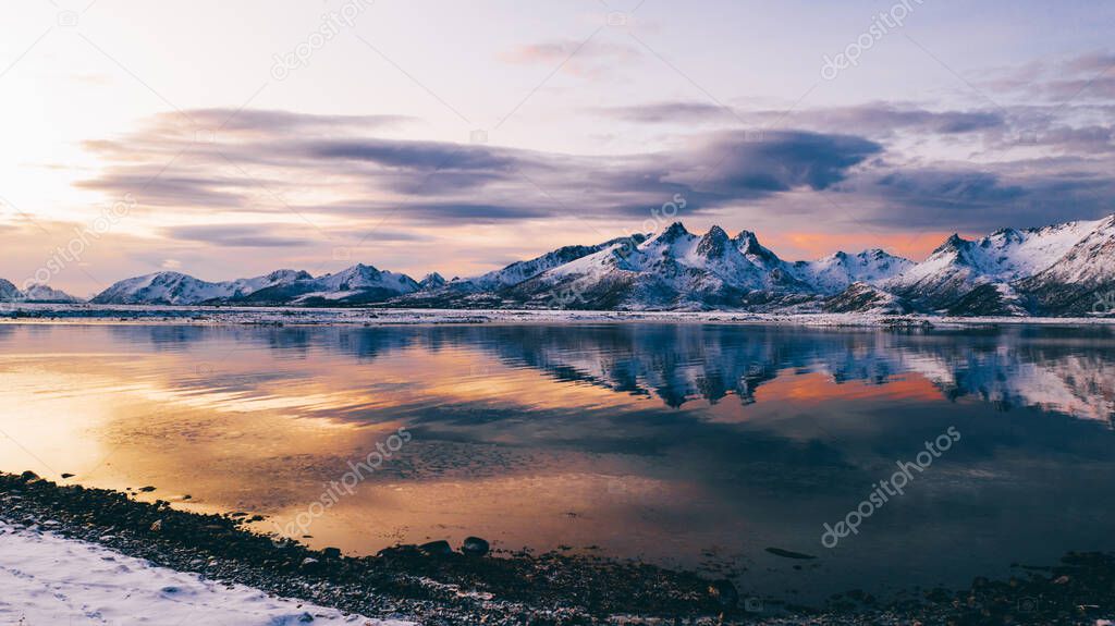 Breathtaking bird's eye view of high mountain rocky peaks covered with white snow reflected in Norway sea water. Breathtaking panoramic fjords landscape of Lofoten in winter, calm beauty of nature 