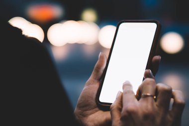 Şehirde gece yol kenarında dururken cep telefonuyla mesajlaşan kimliği belirsiz kadınları boş ekran ile kırpın