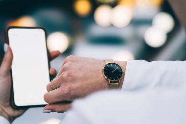 Analog kol saatini kontrol ederken, resmi kıyafetli, elinde dijital cep telefonu olan kimliği belirsiz bir kadın gün içinde şehir sokaklarında dolaşacak.