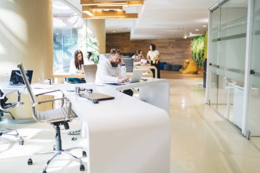 Çağdaş çalışma alanında resmi olarak çalışan erkek yönetici giyimi üzerine kafa yormak ve yoğun iş arkadaşlarının arka planında netbook yazarken proje stratejisini düşünmek