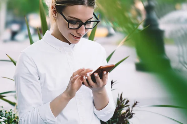 Gröda Positiva Unga Kvinna Vit Skjorta Och Glasögon Bläddra Mobiltelefon — Stockfoto