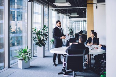 İspanyol işadamı erkek ve kadın çalışanlarla eğitim konferansı yapıyor. Şirket raporundan strateji bilgilerini açıklıyor. Bir grup deneyimli insan verimli takım çalışmalarını tartışıyor.