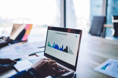 Erkek analistin iş bilgisini incelerken laptoptaki istatistikler, ağ defteri üzerinden web grafik grafiklerini kontrol eden yetenekli tüccar ve bilgisayar istatistikleri ile kesilen resmi