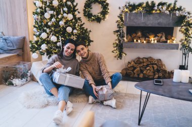 Gri masa ve şöminenin yanında oturan ve yerde çelenkler ve yakacak odunlarıyla süslenmiş tatmin olmuş kadın arkadaşlarının yukarısından.