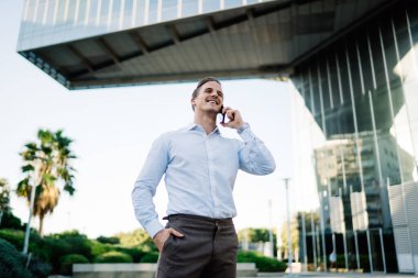 Başarılı bir iş adamı, gezgin, mutlu, beyaz gömlekli genç bir müdürün mobil uygulama aracılığıyla danışman ile iletişim kurarak sokakta durması çağrısında bulunuyor.