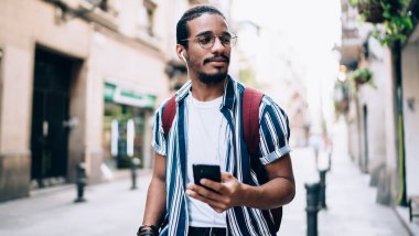 Düşünceli koyu tenli hippi, akıllı telefon çalma listesinden müzik dinleyen yakışıklı milenyum erkeği, cep telefonu ve aksesuar kullanarak sesli kitap okumaya odaklanmış.