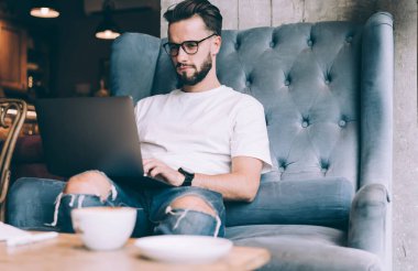 Uzaktan kumanda sırasında göz düzeltme programı kodunu sağlamak için optik gözlüklerdeki erkek bilişim yazılım geliştiricisi, netbook sosyal medya ağında yetenekli blog yazarı