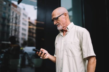 Şehir merkezinde boş zamanlarında alınan e-postaları kontrol etmek için optik göz giysisi içindeki yaşlı beyaz blog yazarı, cep telefonlarını taramak için 4G 'ye bağlanan olgun erkek kullanıcı