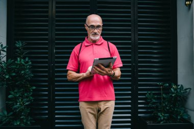 Çevrimiçi modda sohbet ve mesajlaşma için 4G 'ye bağlanan yaşlı blogcu, klasik gözlüklü son sınıf öğrencisi, kentte ayakta duran modern dokunmatik bloknotlardan e-posta aldı