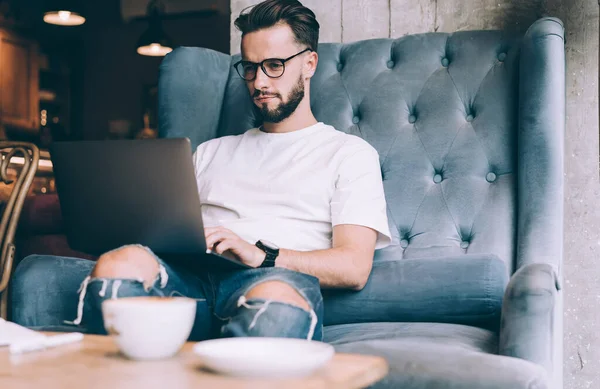 Uzaktan kumanda sırasında göz düzeltme programı kodunu sağlamak için optik gözlüklerdeki erkek bilişim yazılım geliştiricisi, netbook sosyal medya ağında yetenekli blog yazarı