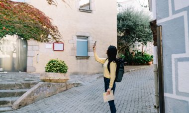 Günümüz sırt çantalı gezgininin modern cep telefonu teknolojisini kullanarak solo tatiller ve gezintiler sırasında resim fotoğraflarına tıklama, sırt çantalı ve haritalı genç turist web gezici vlog 'u çekiyor.