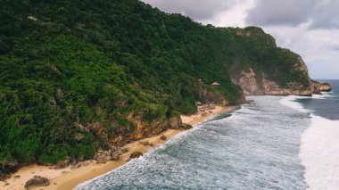 Islak sahilde, bulutlu gökyüzüne karşı gündüz vakti bulutlu ve huzurlu dalgalı denizlerden.