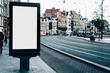 Amsterdam Hollanda 'da eski binaları ve asfalt yolu olan tarihi kentteki asfalt kaldırımda reklam için boş ekranlı modern ilan panosu
