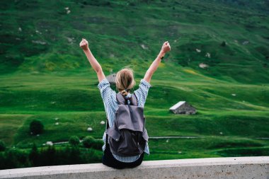 Anonim bir kadın tırmanışçının çimento sınırında otururken kollarını kaldırması ve manzaranın tadını çıkarması.