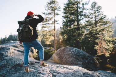 Günbatımında Yosemite Milli Parkı 'nda sırt çantalı ve sırt çantalı, tanınmayan bir erkek gezginin, gün batımına baktığı arka plan.