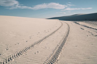 Beyaz Kumlar Ulusal Parkı 'nda, Amerika' daki sakin çölde, mavi bulutlu gökyüzüne karşı tekerleklerin üzerinde izler var.