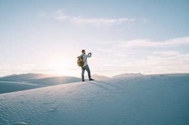 Beyaz Kumlar Ulusal Parkı 'nda sırt çantalı ve arkada fotoğraf çeken tanınmayan bir erkeğin arka plan görüntüsü.