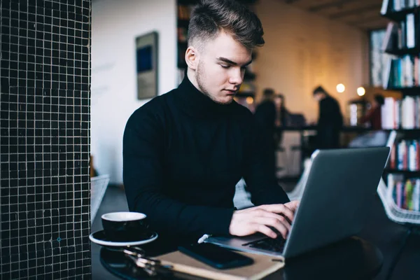 Homem Jovem Concentrado Roupas Casuais Digitando Teclado Netbook Enquanto Sentado — Fotografia de Stock