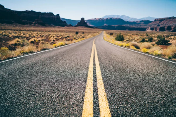 道路上の岩と米国の乾燥砂漠の谷を通って実行している二重固体と空のアスファルト道路の上から — ストック写真