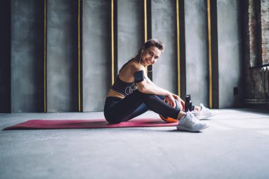 Spor giyim kuşamında spor giyinen, spor salonunda antrenmandan sonra müzik dinleyen mutlu bir kadının yan görüntüsü.