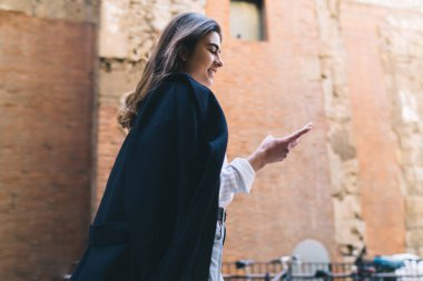 Beyaz tenli genç turistin sohbet etmek ve mesajlaşmak için hücresel uygulamayı kullanarak şehri keşfetmek için tek başına seyahat etmesinden keyif almasının yanı sıra, akıllı telefondan okuyan güzel hippi kız