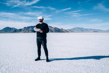 Utah eyaletinde tatil yaparken modern kablosuz taşınabilir tablet ve sanal gerçeklik gözlüğü kullanan erkek turistlerin tam uzunluğu