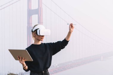 Belirsiz kadın ressam sisli havaya karşı Golden Gates yakınlarında duruyor ve proje üzerinde çalışırken sanal gerçeklik gözlüğü kullanıyor.