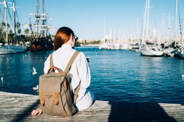 Milenyum kadınlarının modaya uygun kıyafetleriyle liman rıhtımında su seyahatinden sonra dinlenirken ve cep telefonu kullanırken, tatillerde limanda sırt çantalı hippi kız.