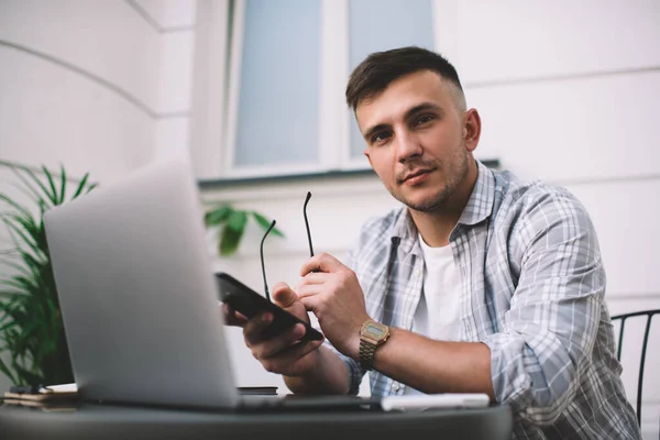 Hombre Ropa Casual Sosteniendo Teléfono Móvil Gafas Las Manos Mientras — Foto de Stock