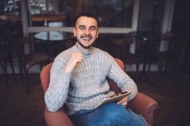 Yukardan gelen sakallı, uzaktan kumandalı bir işçi koltukta oturmuş, düşüncelerini yazarken kameraya bakıyor.