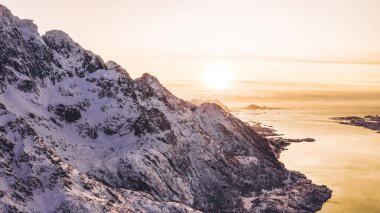 Kışın karla kaplı görkemli fiyort dağlarının nefes kesici kuş bakışı görüntüsü. Hava manzaralı kaya zirveleri, resim gibi güzel doğa manzarası. Lofoten Adası İskandinav Denizi ile çevrilidir